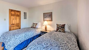 A room with two beds, a wooden door, a wall-mounted picture, and a bedside lamp. - El Prado Townhome w/ View of Taos Mountains! (El Prado)