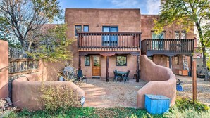 A two-story building with a balcony, a door, and a table with chairs in the front yard. - El Prado Townhome w/ View of Taos Mountains! (El Prado)