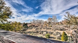 A wooden deck overlooking a dry, hilly landscape with sparse vegetation and a clear blue sky. - El Prado Townhome w/ View of Taos Mountains! (El Prado)