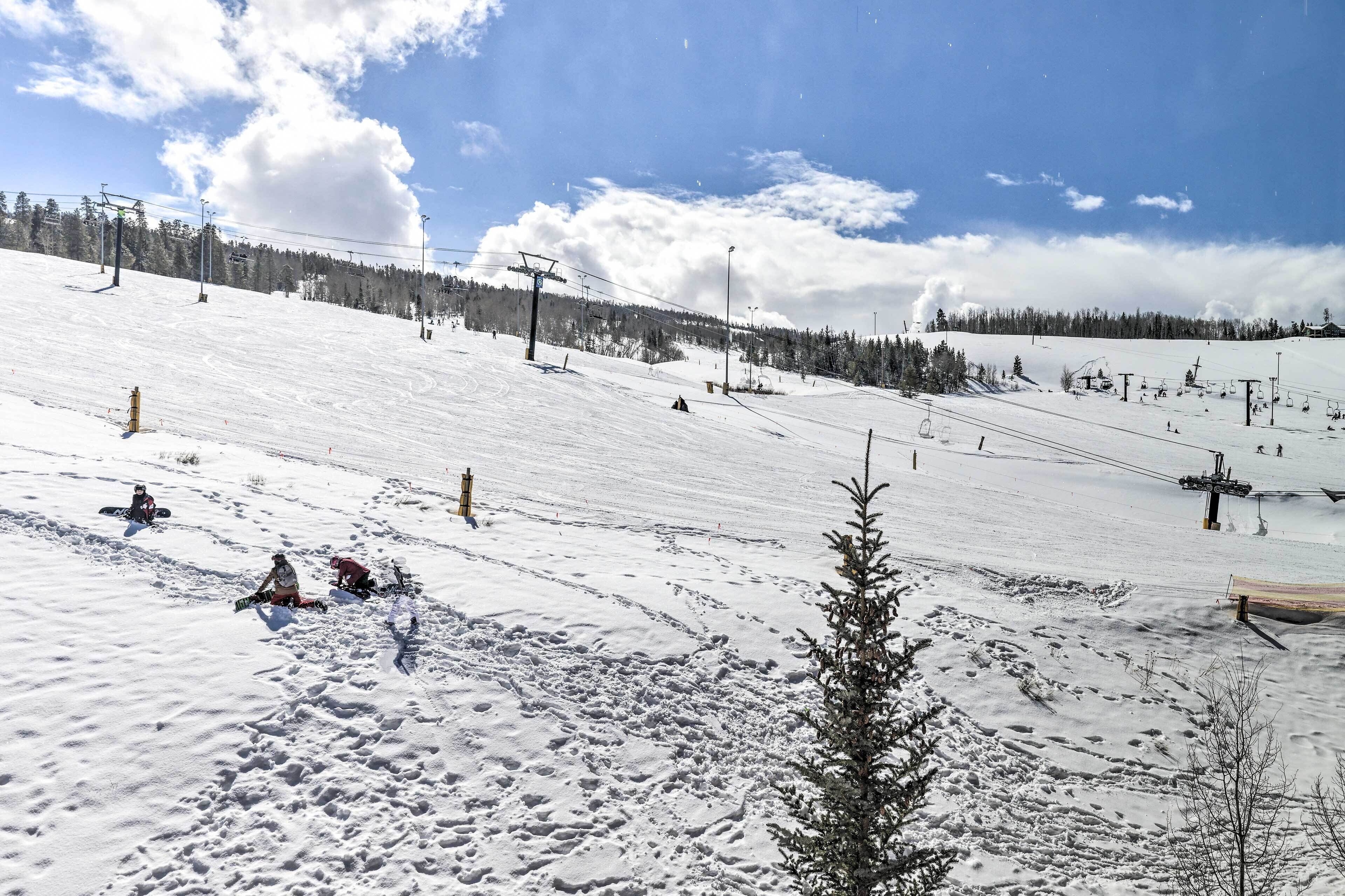A snowy ski slope with ski lifts and trees in the background.