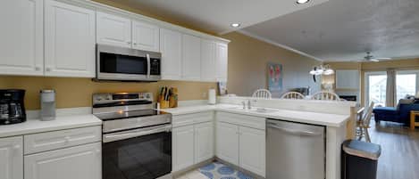 A modern kitchen with white cabinets, stainless steel appliances, and a blue patterned backsplash.