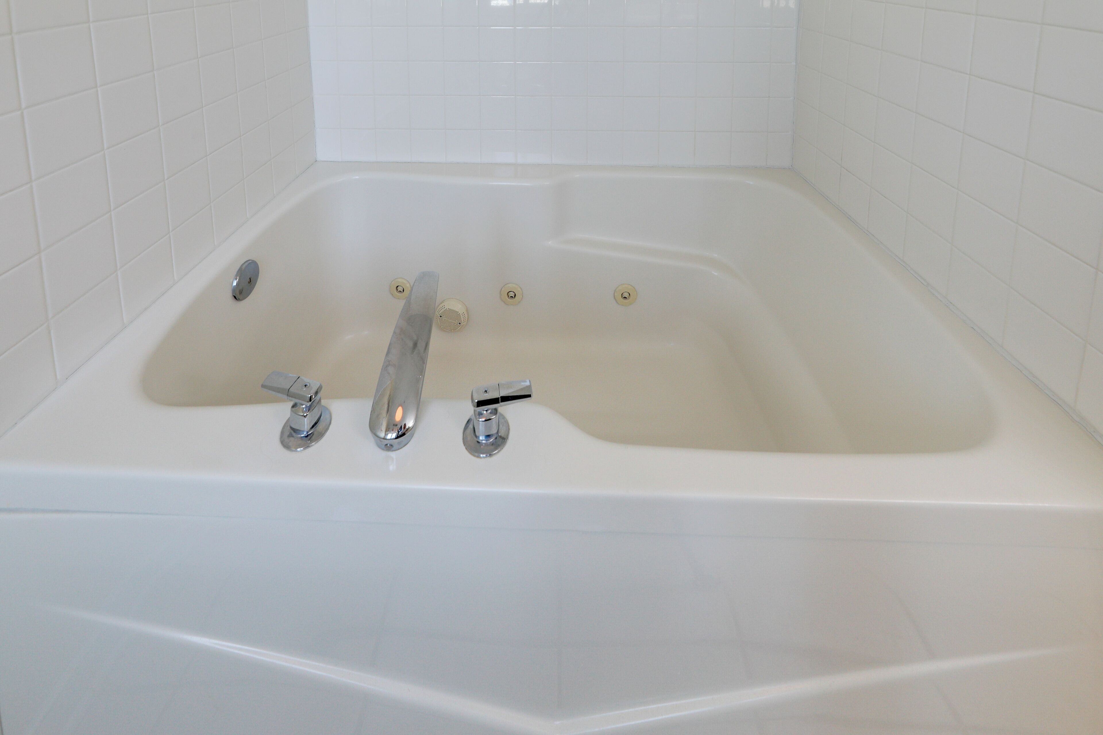 A white bathtub with two faucets and a drain.