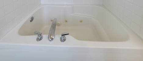 A white bathtub with two faucets and a drain.