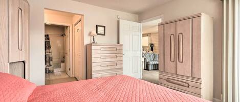 A bedroom with a large bed, a wardrobe, a dresser, and a ceiling fan.