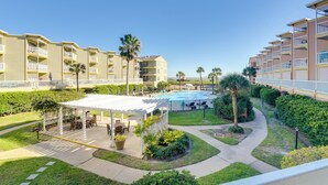 A hotel courtyard with a pool, outdoor seating, and a covered patio area. - Walk to Galveston Beach: Resort Condo w/ Perks! (Galveston)