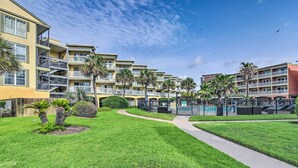A multi-story hotel with balconies, a swimming pool, and well-maintained lawns. - Walk to Galveston Beach: Resort Condo w/ Perks! (Galveston)