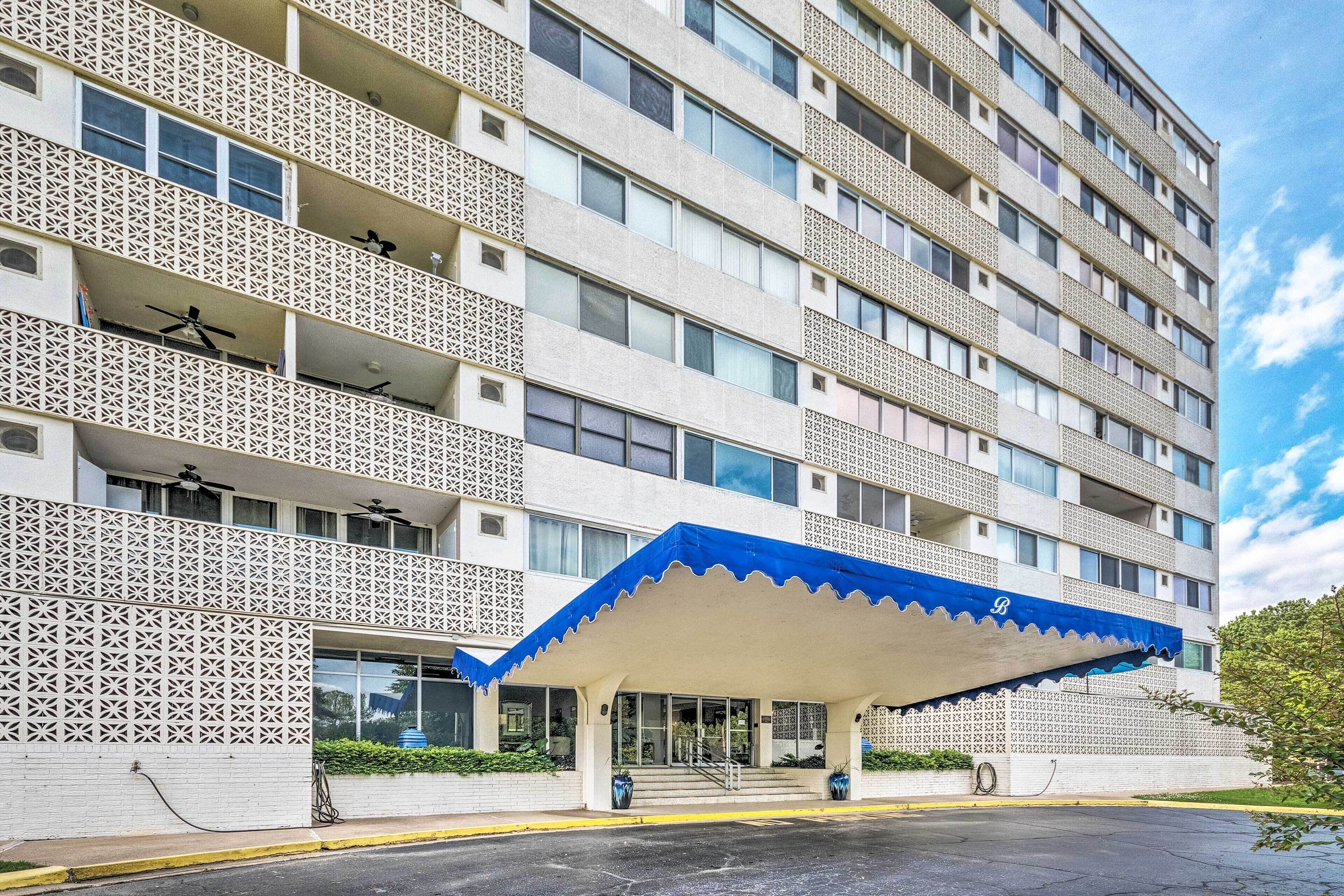 A multi-story hotel with a patterned facade, a covered entrance, and a clear sky.