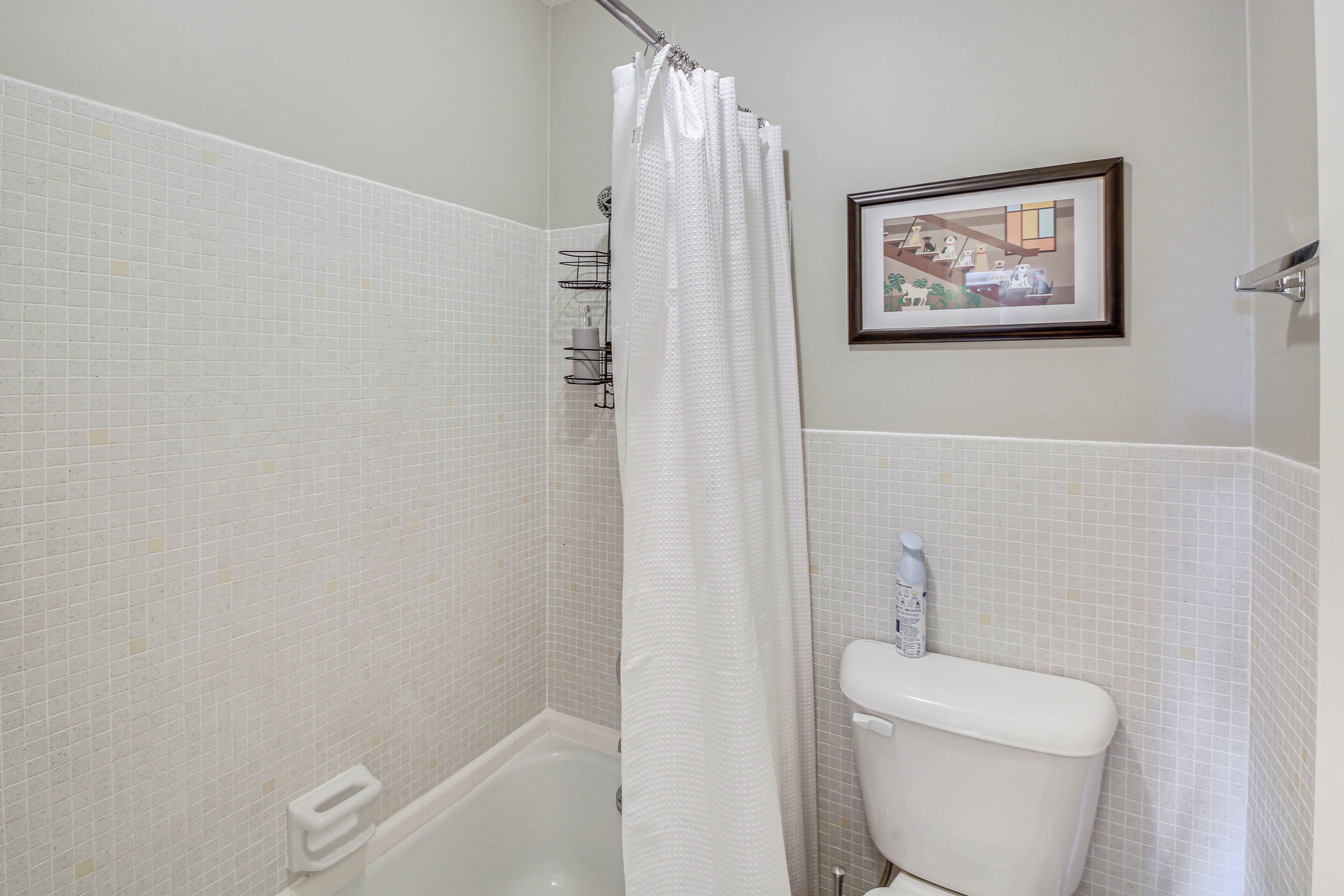 Une salle de bain avec une douche carrelée de carreaux blancs, une baignoire blanche et des toilettes blanches.