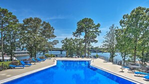 A swimming pool with blue chairs and a view of the water.
