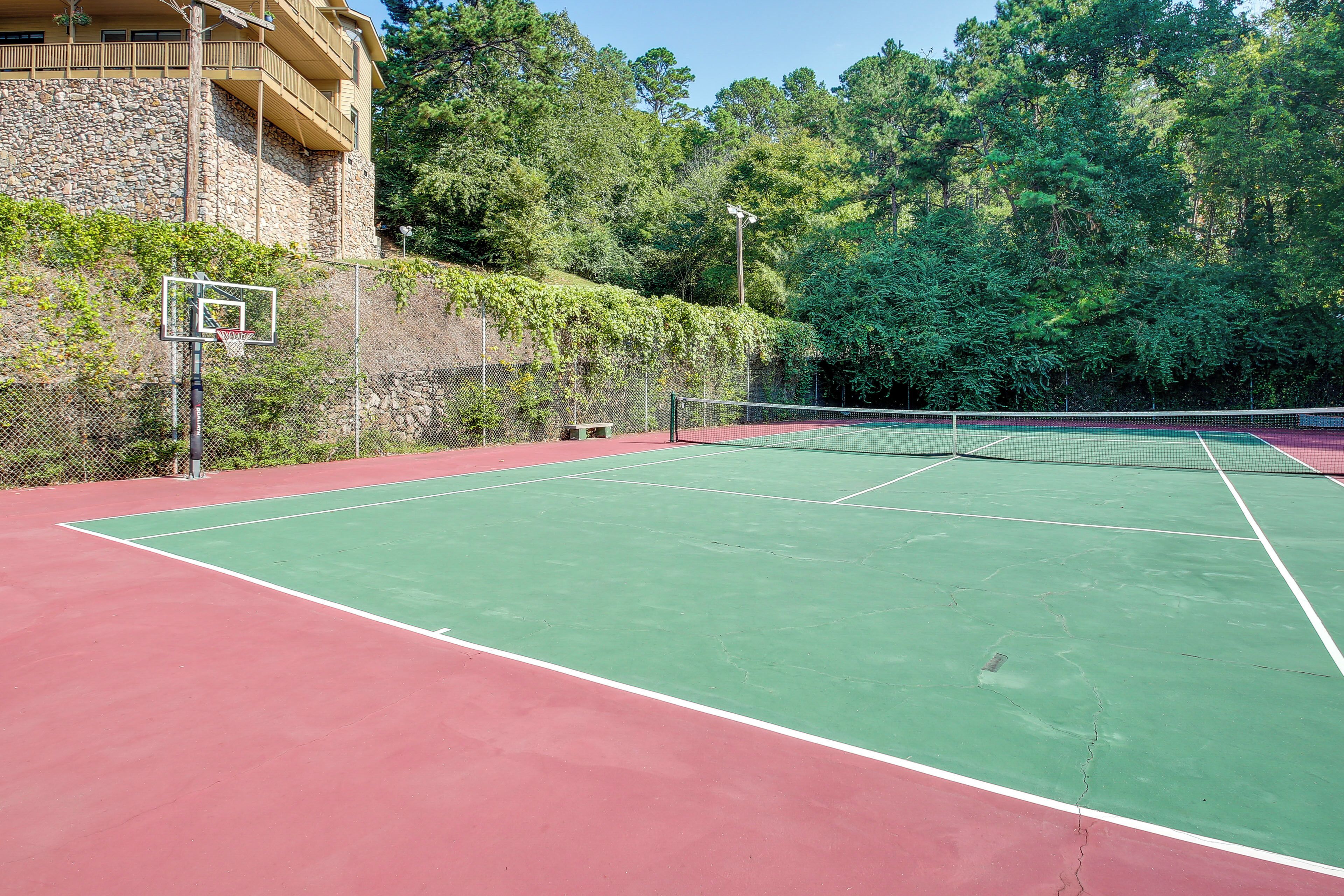 Een tennisbaan met een stenen muur en groen op de achtergrond.