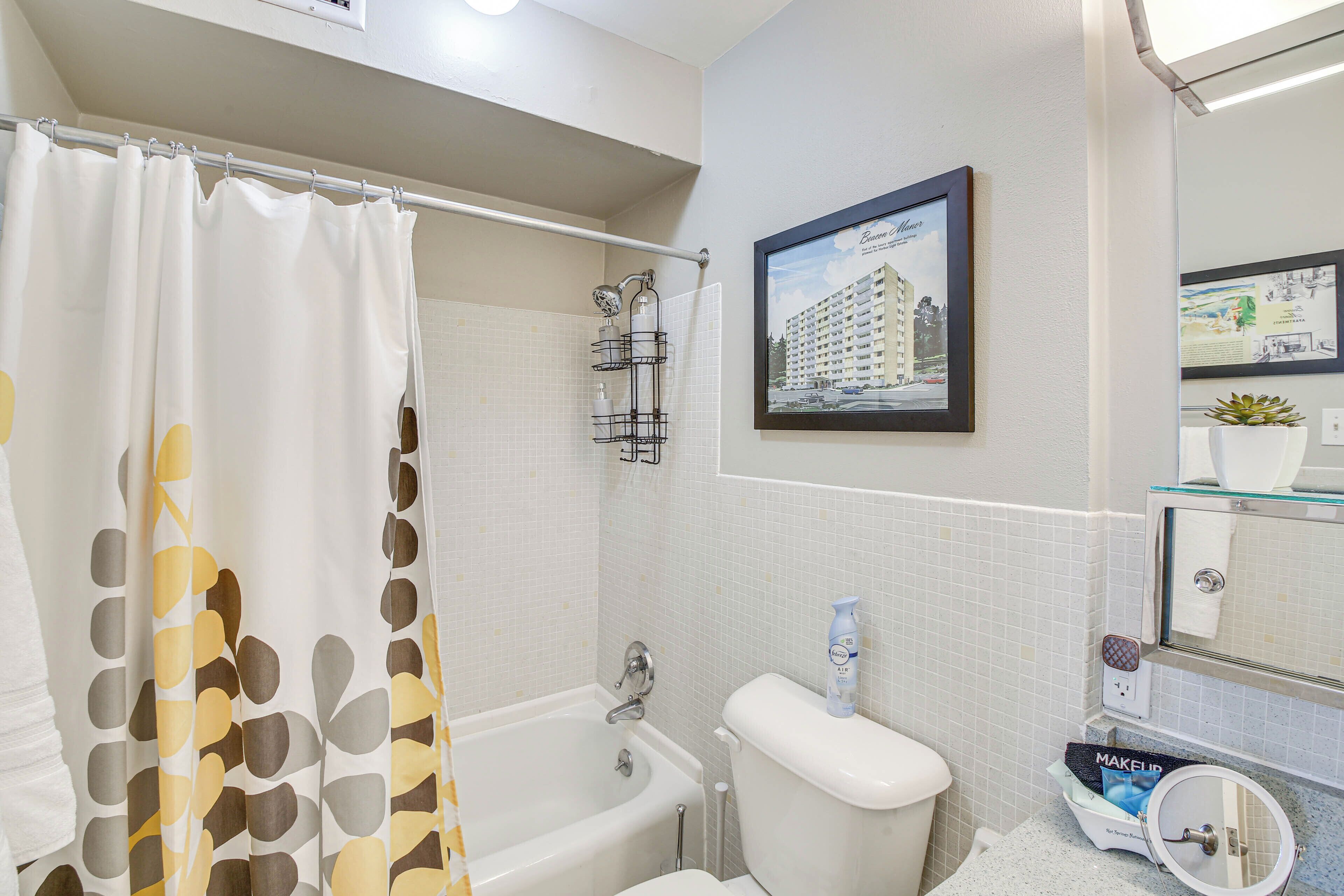 A bathroom with a bathtub, toilet, and a framed picture on the wall.