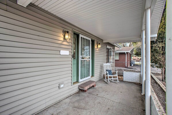 A house with a covered porch, a front door with green shutters, and a small brick building in the background. - Walkable Neighborhood: Family Home in Wheat Ridge (Wheat Ridge)