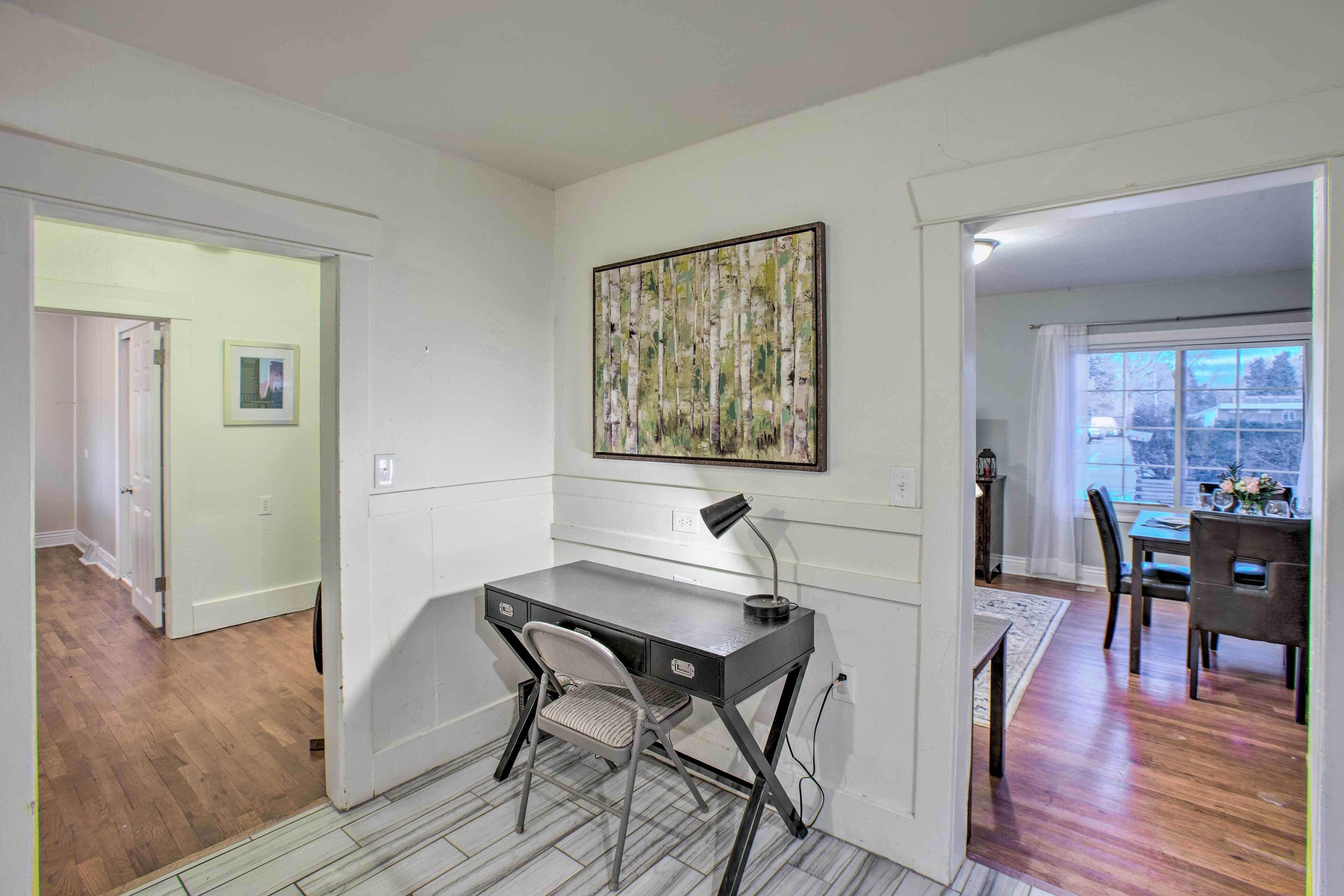 A room with a desk, chair, and a painting on the wall.
