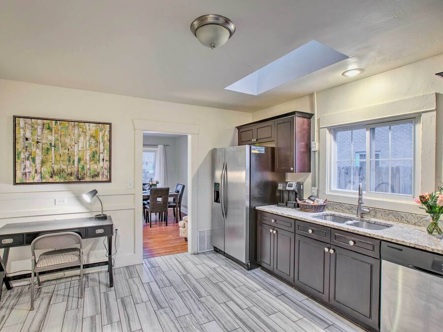 A modern kitchen with a built-in desk, a refrigerator, and a window.