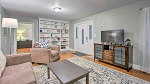 Un salon comprenant un canapé, une table basse, un téléviseur, une bibliothèque et une porte ornée d’un panneau de verre décoratif.