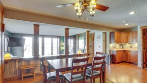 A spacious kitchen with wooden cabinets, a dining area with a large table and chairs, and a ceiling fan with lights.