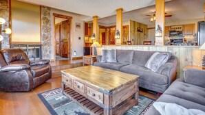A cozy living room with a leather recliner, a wooden coffee table, and a grey sofa.