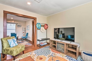 A living room with a green armchair, a TV, a coffee table, and a patterned rug.