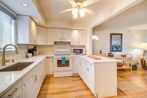 A modern kitchen with white cabinets, a built-in oven, a microwave, and a ceiling fan.