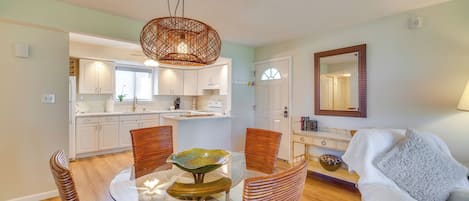 A modern kitchen with white cabinets, a glass dining table, and a unique woven light fixture.