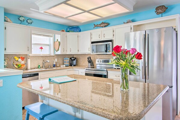 A kitchen with white cabinets, stainless steel appliances, a granite countertop, and a blue accent wall. - South Padre Home w/ Pool & Hot Tub: Walk to Beach! (South Padre Island)