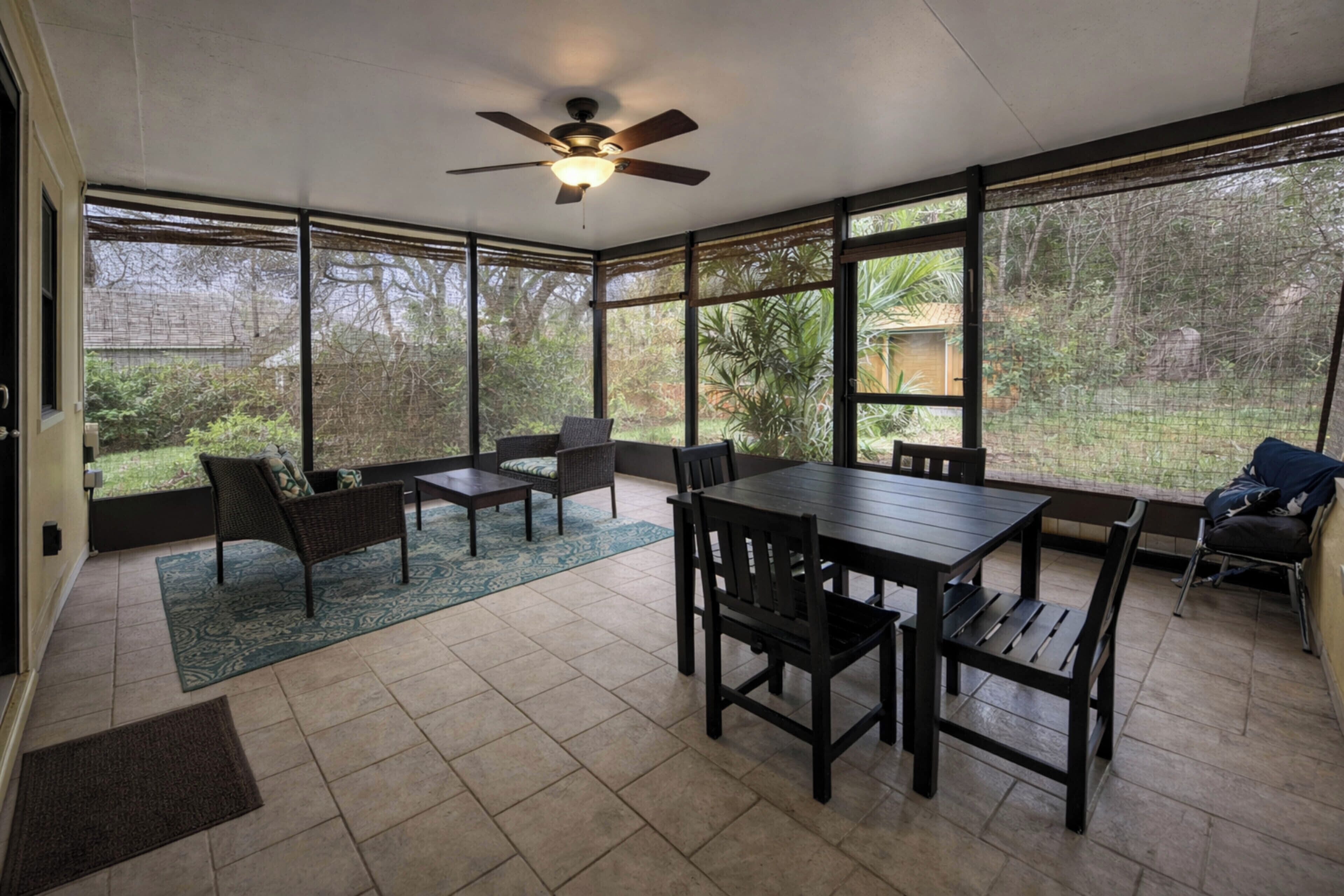 A sunroom with a dining table, chairs, a ceiling fan, and large windows.
