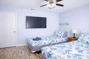 A bedroom with two beds, a ceiling fan, a flat-screen TV, and a door. - Sleeps 9 Walk to Beach St. Augustine Home (St. Augustine)