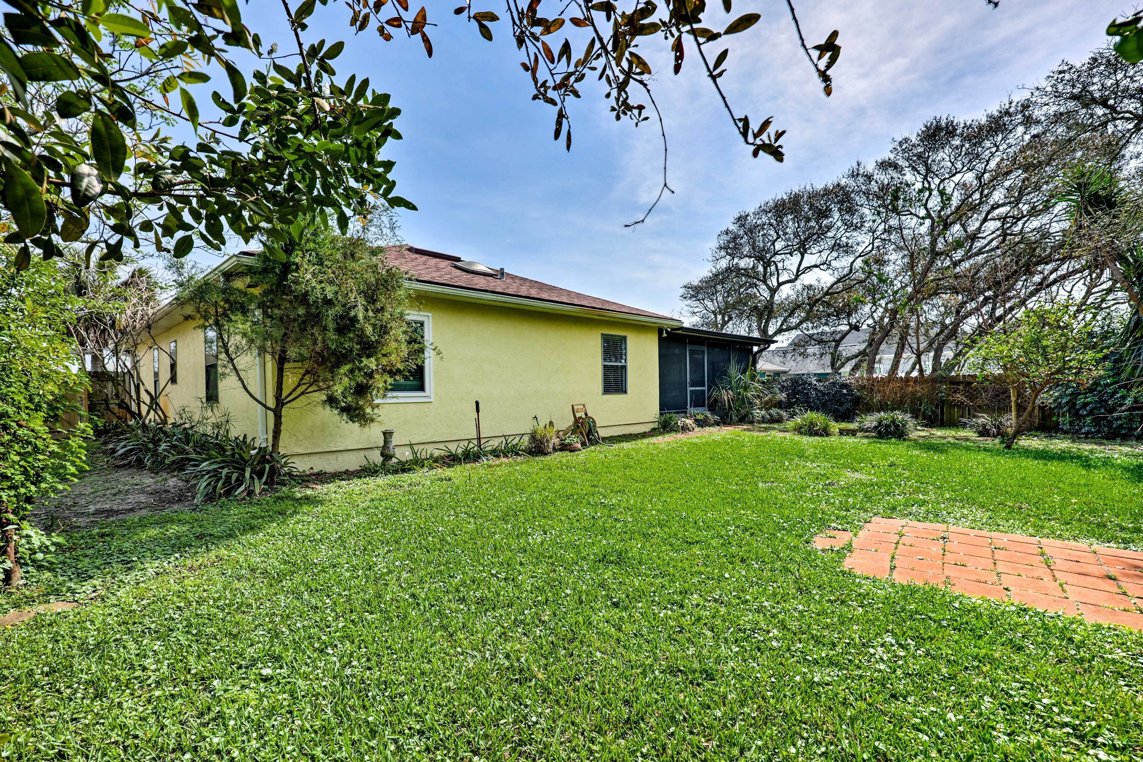 A yellow house with a red brick pathway in a well-maintained garden.