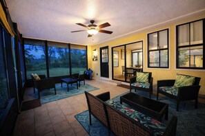 A sunroom with large windows, a ceiling fan, and outdoor seating.