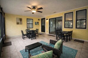 A covered patio area with a ceiling fan, two dining tables with chairs, a sofa, and a small table. - Sleeps 9 Walk to Beach St. Augustine Home (St. Augustine)