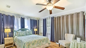 Ein Schlafzimmer mit Bett, Sessel, Tisch und Deckenventilator.