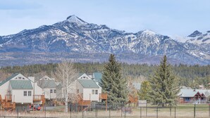 Zona residencial con casas que tienen techos verdes y terrazas de madera, con montañas nevadas al fondo.