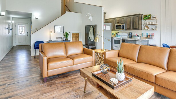 Amplia sala de estar con un sofá de cuero marrón, una mesa de centro de madera y una escalera que conduce a otro nivel.