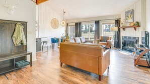 Amplia sala de estar con un sofá grande, piso de madera, chimenea y un comedor con una silla y una mesa azules.