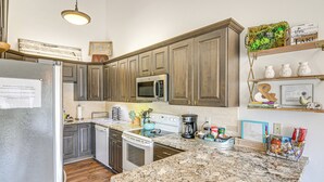 Una cocina con encimeras de granito, electrodomésticos de acero inoxidable y armarios de madera.