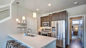 A modern kitchen with a large island, stainless steel appliances, and pendant lighting. - 'rendezvous Buckhorn Cabin' By Hiking Trails (Fraser)
