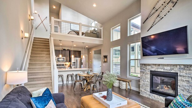 A spacious living area with a high ceiling, a fireplace, a large TV, and a dining area with a kitchen in the background. - 'rendezvous Buckhorn Cabin' By Hiking Trails (Fraser)
