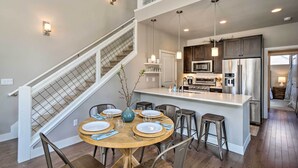 A modern kitchen with a central island, stainless steel appliances, and a dining area with a round table and chairs. - 'rendezvous Buckhorn Cabin' By Hiking Trails (Fraser)