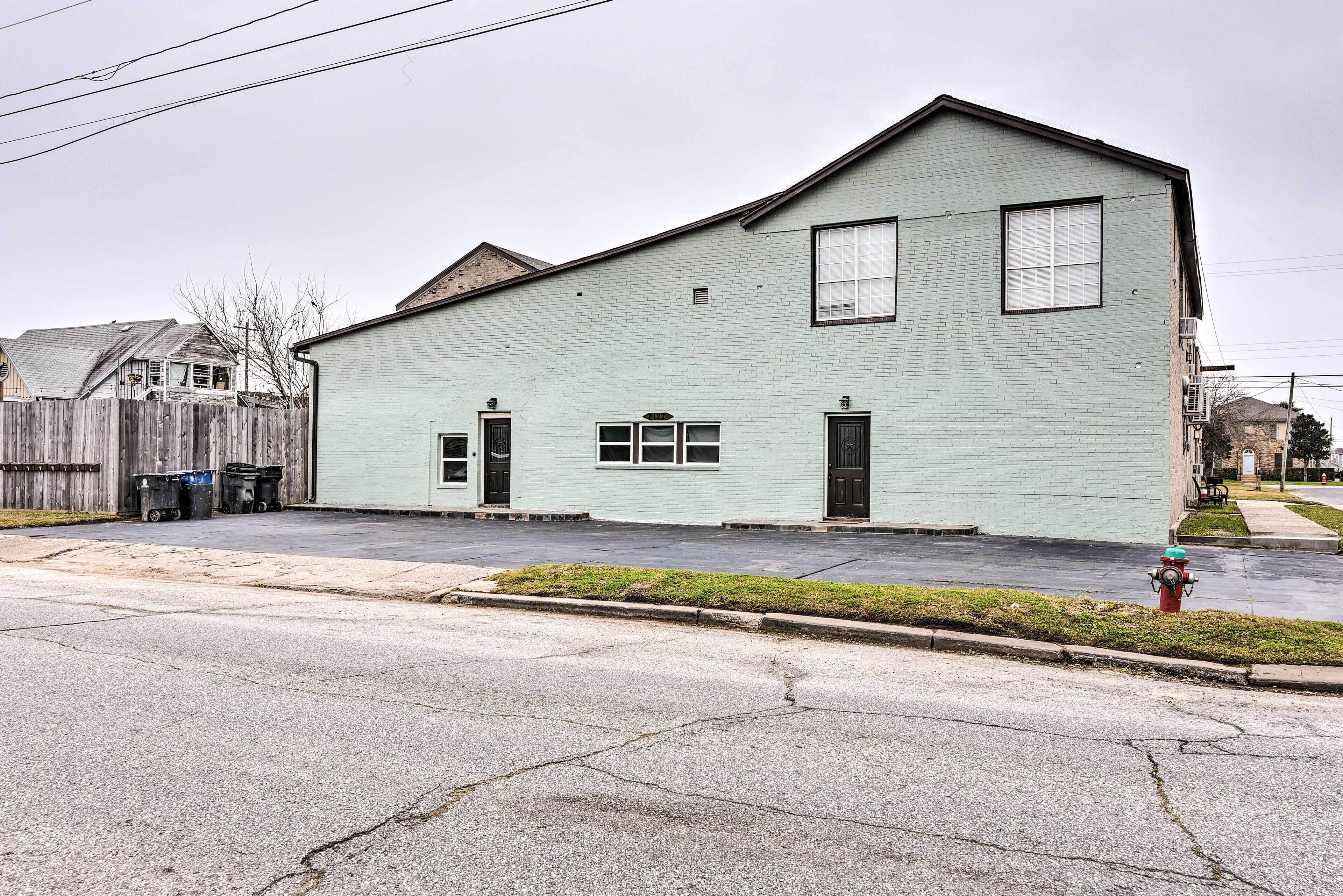 A two-story building with a light blue exterior, a fire hydrant in front, and a wooden fence to the left.