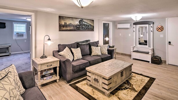 A living room with a grey sofa, a wooden coffee table, a lamp, and a painting on the wall. - Walkable Galveston Apartment w/ Hot Tub Access (Galveston)