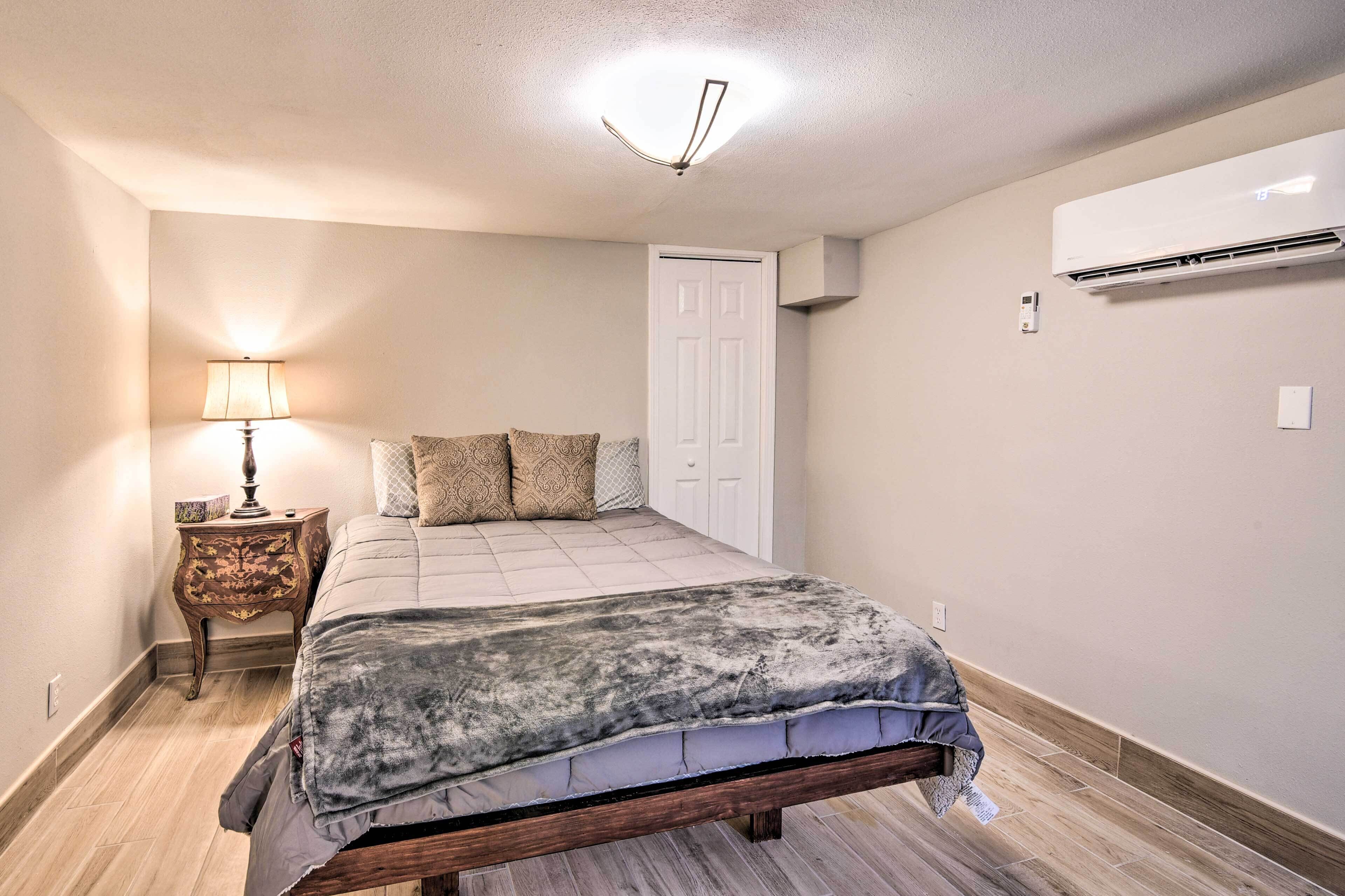 A bedroom with a bed, bedside lamp, and an air conditioning unit.