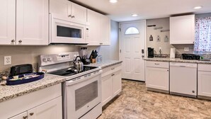 A modern kitchen with white cabinetry, a built-in microwave, stainless steel appliances, and a granite countertop. - Walkable Galveston Apartment w/ Hot Tub Access (Galveston)