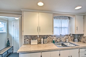 A kitchen with white cabinets, a toaster, a sink, and a window with a curtain. - Lovely Tacoma Cottage w/ Fire Pit, Near Dtwn! (Tacoma)