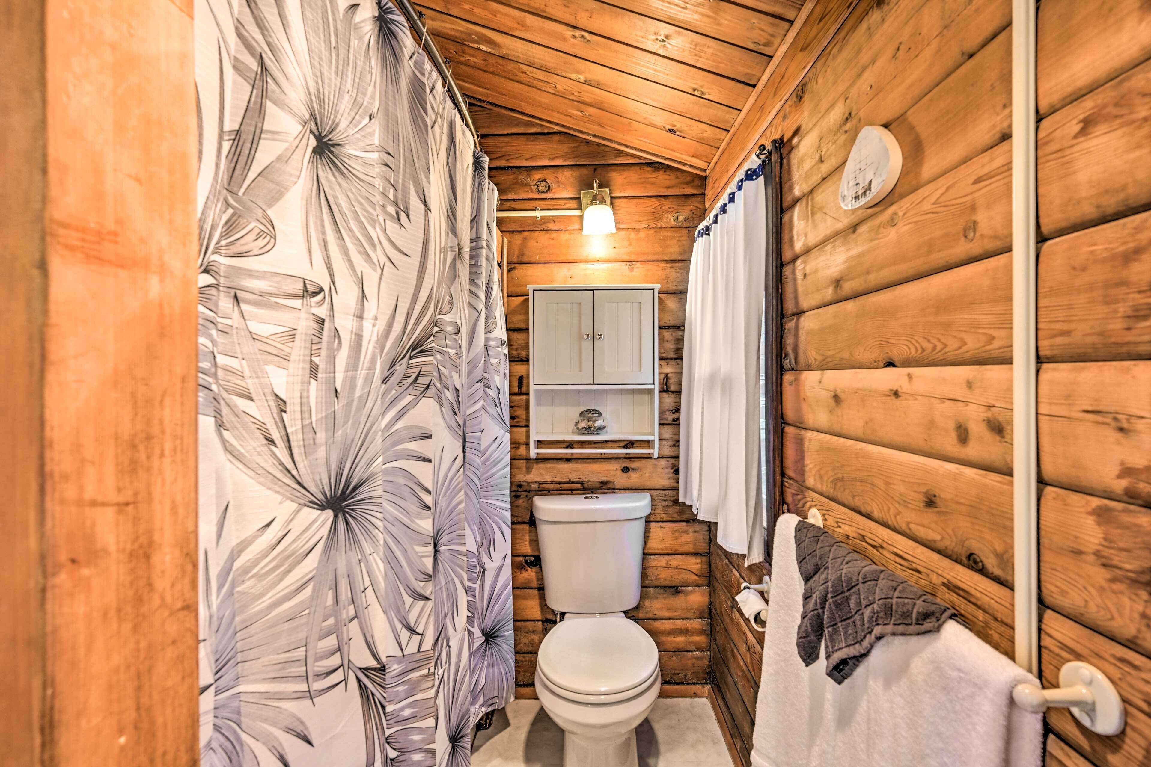 Ein Badezimmer einer Holzhütte mit Toilette, einem Regal darüber und einem Handtuchhalter.