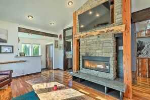 Un salon moderne avec une cheminée en pierre, des poutres en bois et une grande fenêtre.