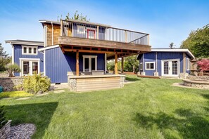 Une maison à deux étages avec une terrasse en bois et des fondations en pierre.