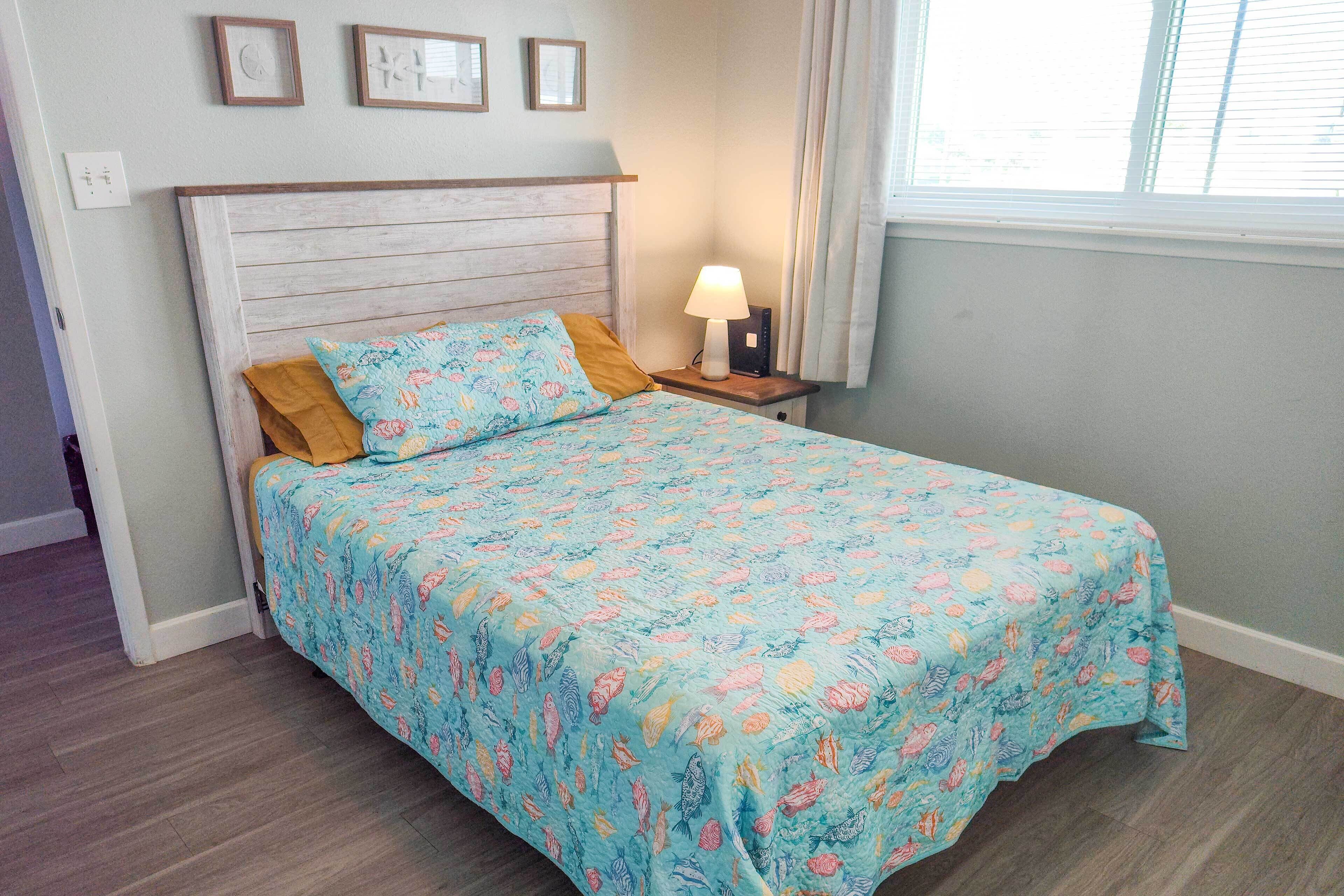 A bedroom with a bed, a nightstand, a lamp, and a window with curtains.