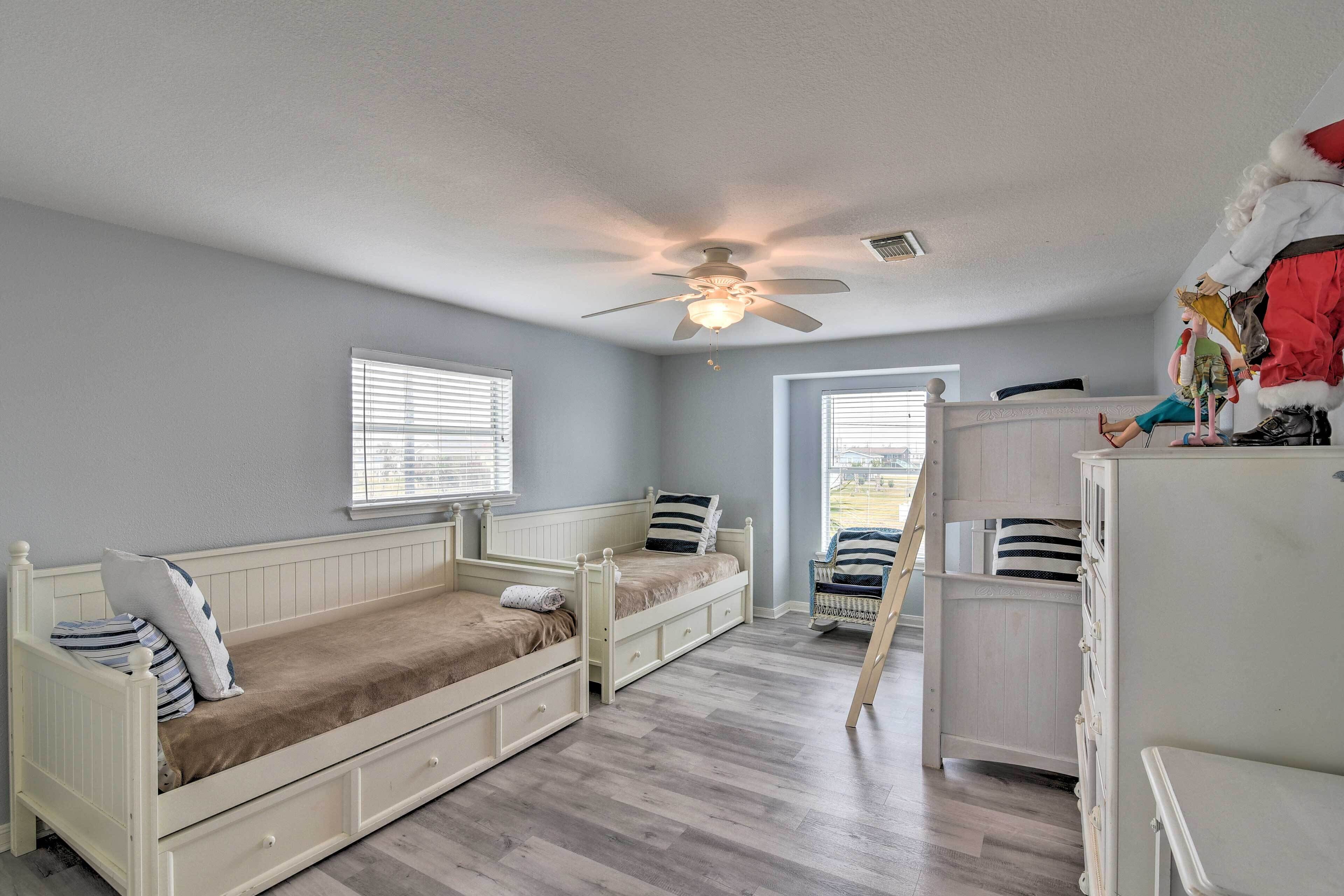 A bedroom with two white single beds, a ceiling fan, and a window with blinds.
