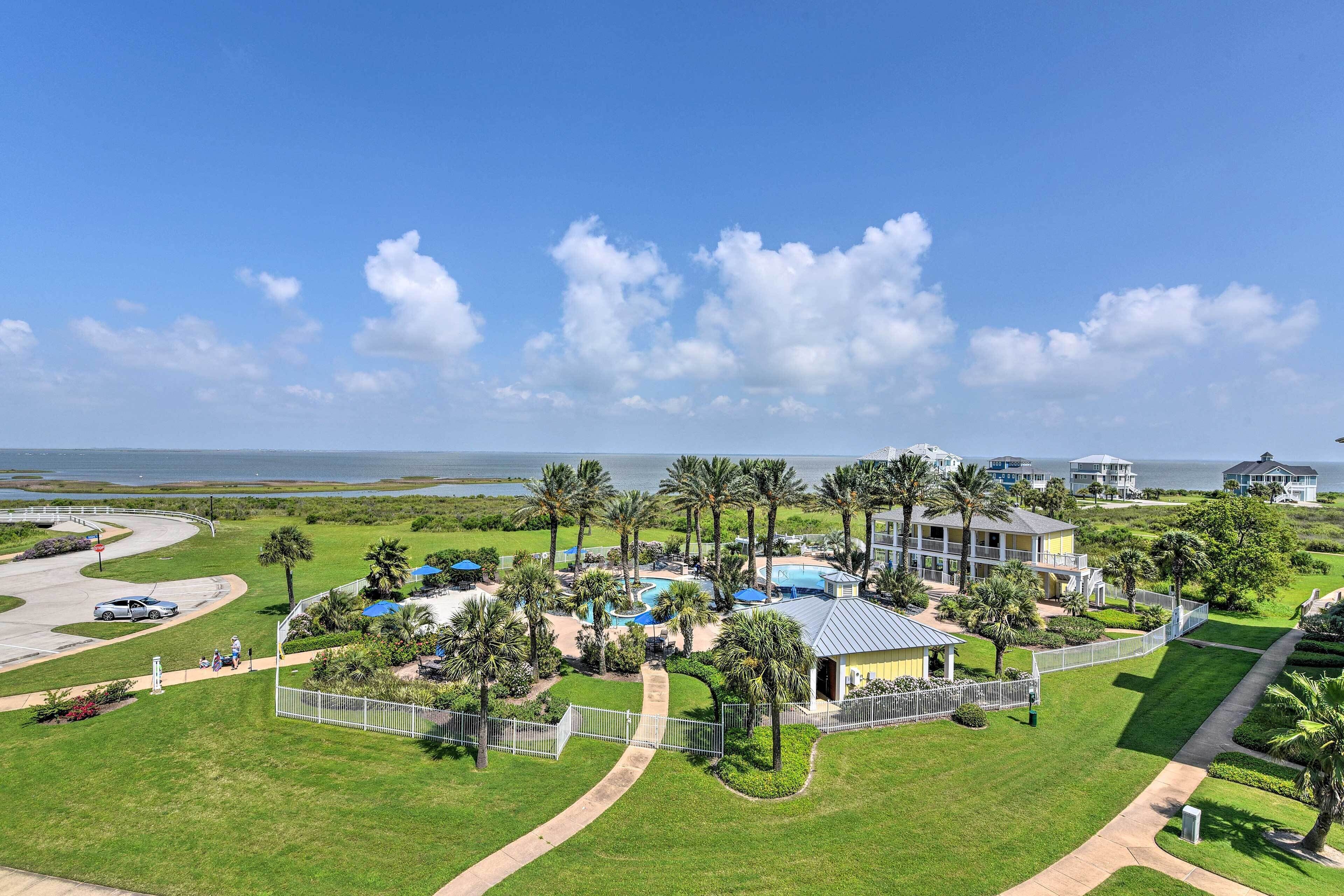 Un resort con piscina, palmeras y vista al océano.