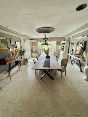 A dining room with a long wooden table, chairs, and a chandelier.